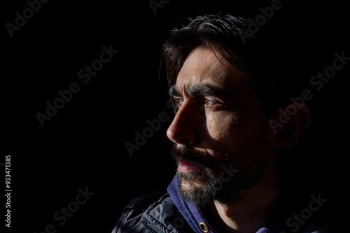 rostro lateral con mirada seria de hombre sobre fondo oscuro 