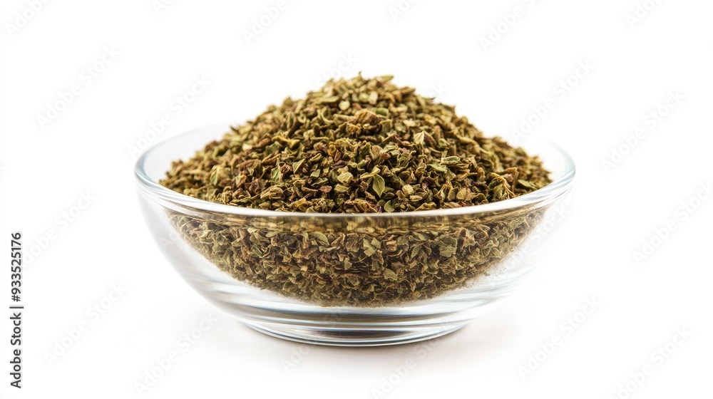 A small glass bowl of dried oregano, isolated on a white background, with the crushed herbs piled high inside the clear container. A small glass bowl of dried oregano, isolated on a white background, with the crushed herbs piled high inside the clear container.