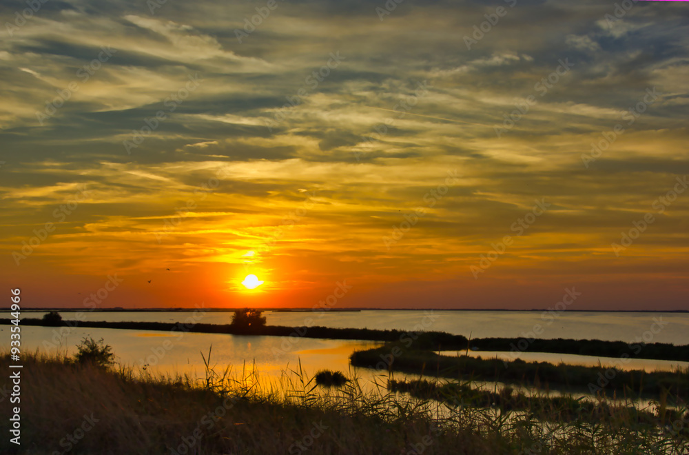 Amazing sunset over the lagoon: reflections on the water and strips of land with wild nature Amazing sunset over the lagoon: reflections on the water and strips of land with wild nature