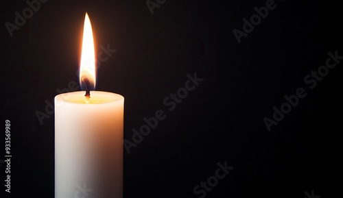 A burning candle shining against a dark background photo