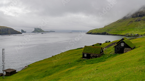 Paisaje de casas feroeses y vistas de Drangarnir ,entre las islas de Vágar y  el islote Tindhólmur en Islas Faroe, un dia de niebla y lluvia fina de Julio photo