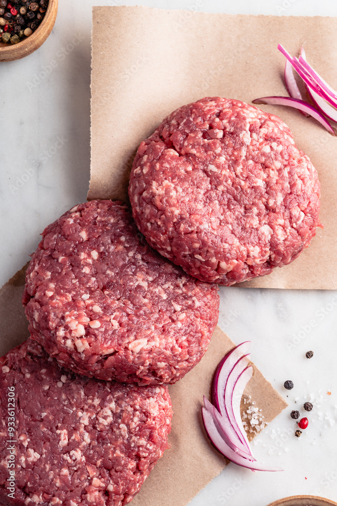 Raw burger steak cutlets on craft paper, high angle view Raw burger steak cutlets on craft paper, high angle view