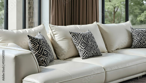 A sleek, white leather sofa set with geometric throw pillows in a minimalist living room with large windows