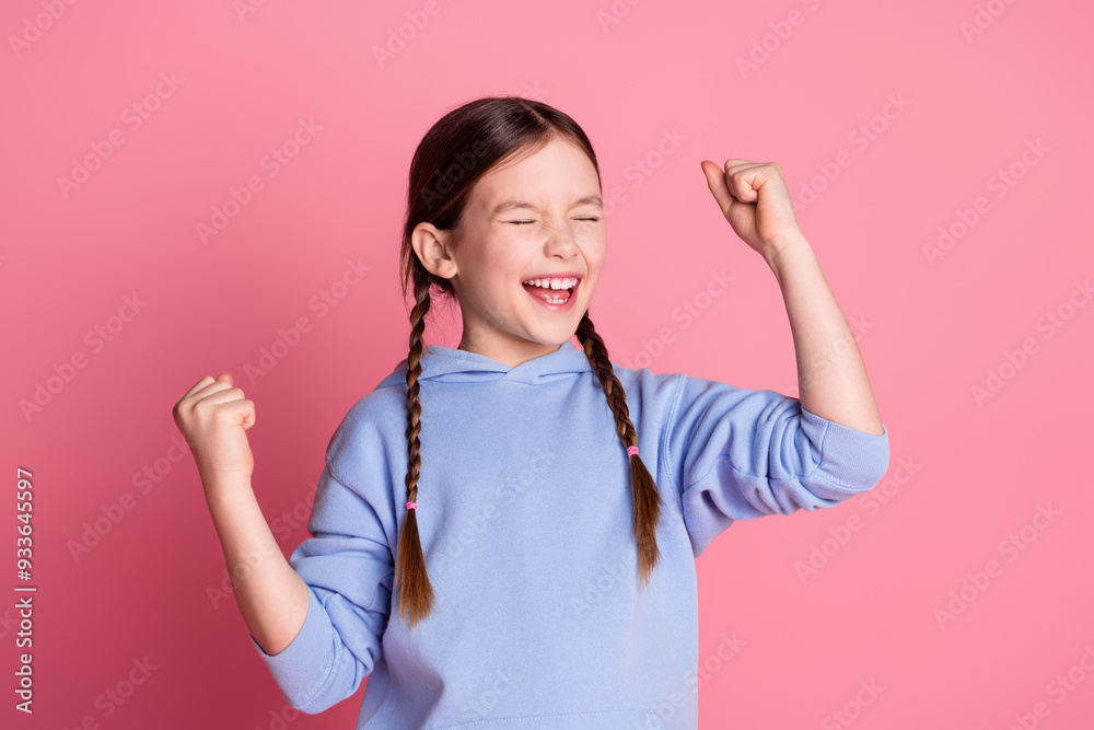 Photo of lovely small schoolkid closed eyes raise fists wear hoodie isolated on pink color background Photo of lovely small schoolkid closed eyes raise fists wear hoodie isolated on pink color background