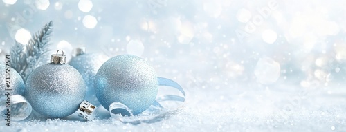 Light blue Christmas balls and silver decorations on white background with bokeh lights