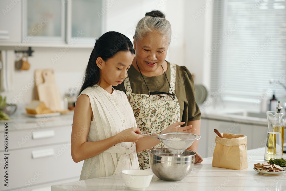 Girl learning to bake cake together with her grandma in the kitchen Girl learning to bake cake together with her grandma in the kitchen