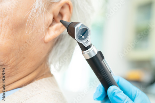 Audiologist use otoscope checking ear of elderly woman patient treating hearing loss problem. photo