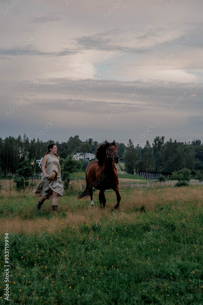 Pregnant girl in dress and straw hat with horse running on farm at sunset Pregnant girl in dress and straw hat with horse running on farm at sunset