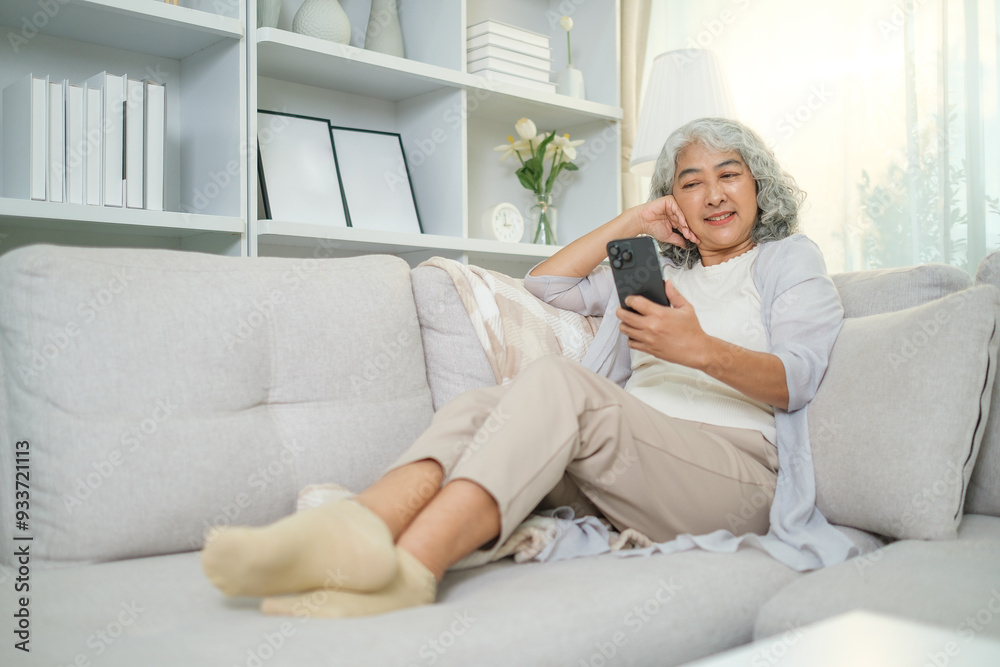 Relaxed senior woman using mobile phone while sitting on comfortable sofa at home. Relaxed senior woman using mobile phone while sitting on comfortable sofa at home.