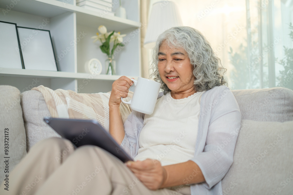 Carefree middle aged woman drinking hot tea and using digital tablet on couch at home. Carefree middle aged woman drinking hot tea and using digital tablet on couch at home.