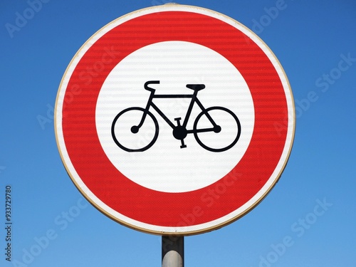 A red circle with a bicycle symbol inside, set against a blue sky, indicating that bicycles are prohibited from entering or using the area
