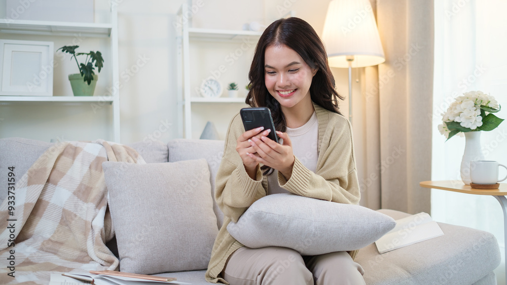 Happy young adult woman using mobile phone on sofa in cozy living room. Happy young adult woman using mobile phone on sofa in cozy living room.