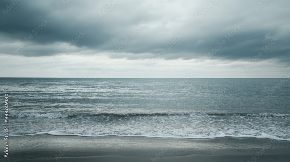 A cloudy grey sky over a calm sea, with waves gently lapping at the shore A cloudy grey sky over a calm sea, with waves gently lapping at the shore