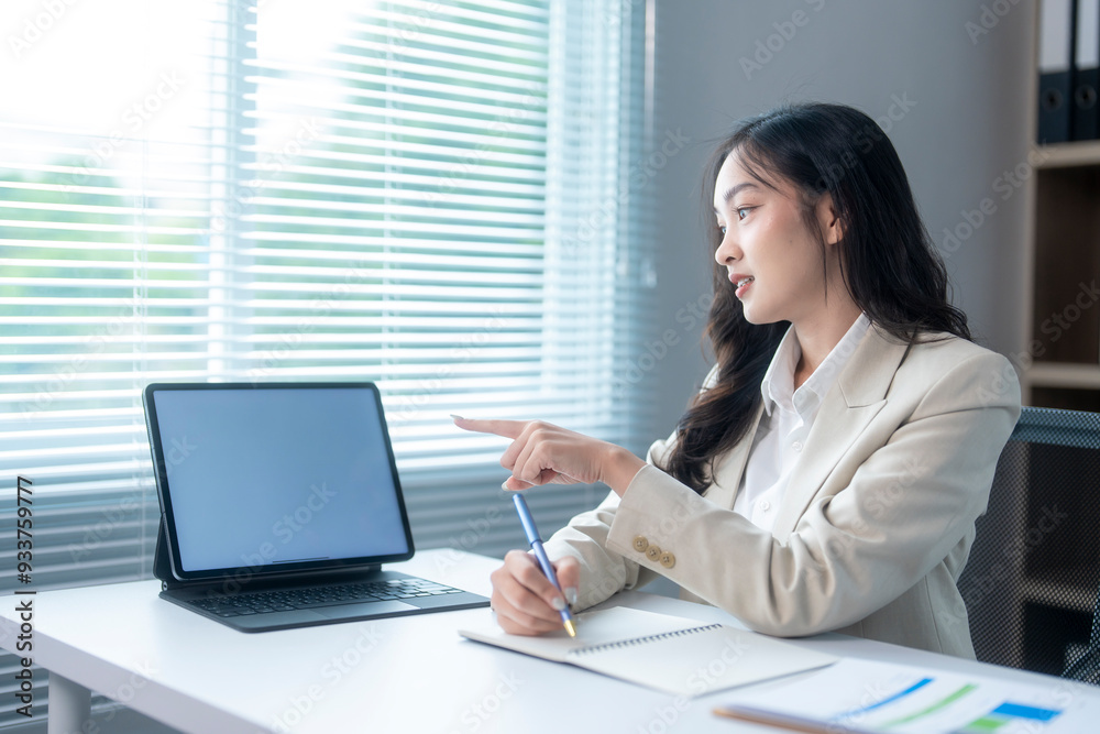 Businesswoman pointing at tablet with blank screen working in office Businesswoman pointing at tablet with blank screen working in office