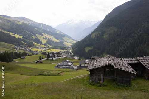 old and new alpine buildings Landscape with old wood sheds and modern houses surrounded by alpine mountains photo