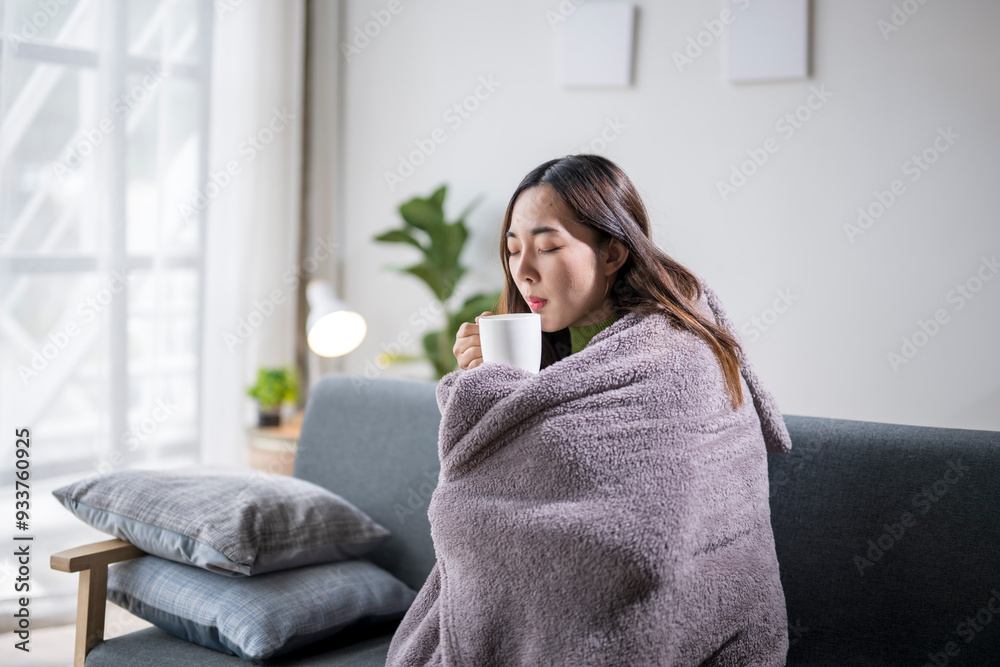 Young woman feeling sick and drinking hot beverage on sofa Young woman feeling sick and drinking hot beverage on sofa