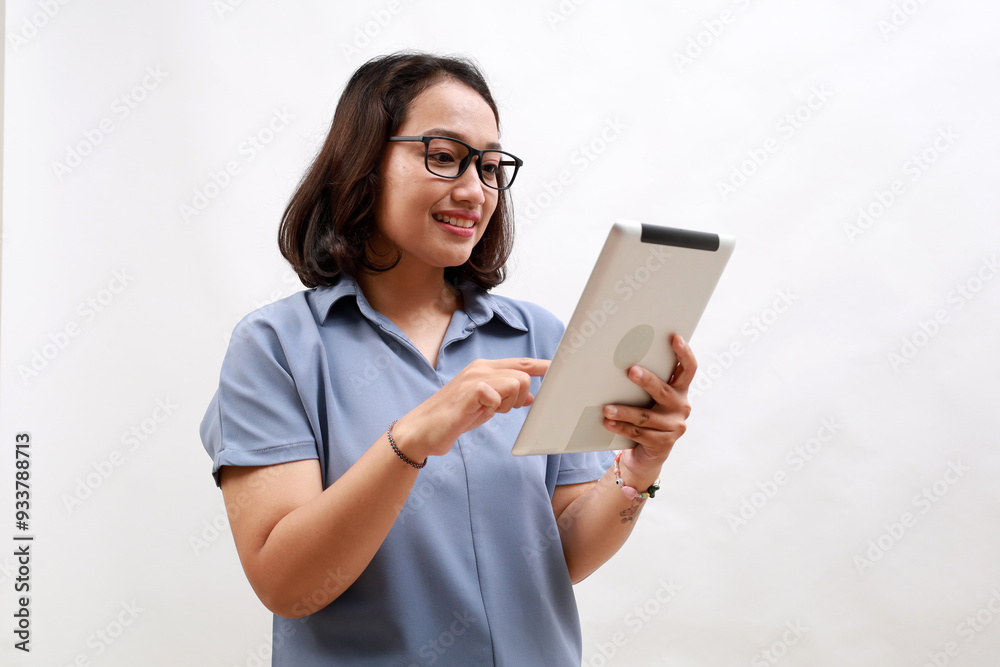 Smiling busy young asian business woman manager using tablet computer, happy business woman executive looking at tab device analyzing finance trading market data working standing over white background Smiling busy young asian business woman manager using tablet computer, happy business woman executive looking at tab device analyzing finance trading market data working standing over white background
