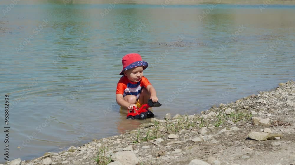 Small child wearing sun protection shirt playing on the lake shore on a summer day. Small child wearing sun protection shirt playing on the lake shore on a summer day.
