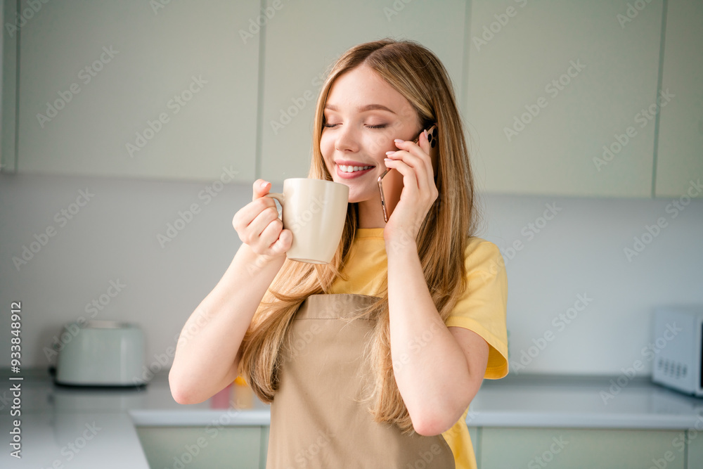 Photo of nice teen girl drink smell coffee talk phone wear apron making domestic homemade dinner interior kitchen house apartment indoors