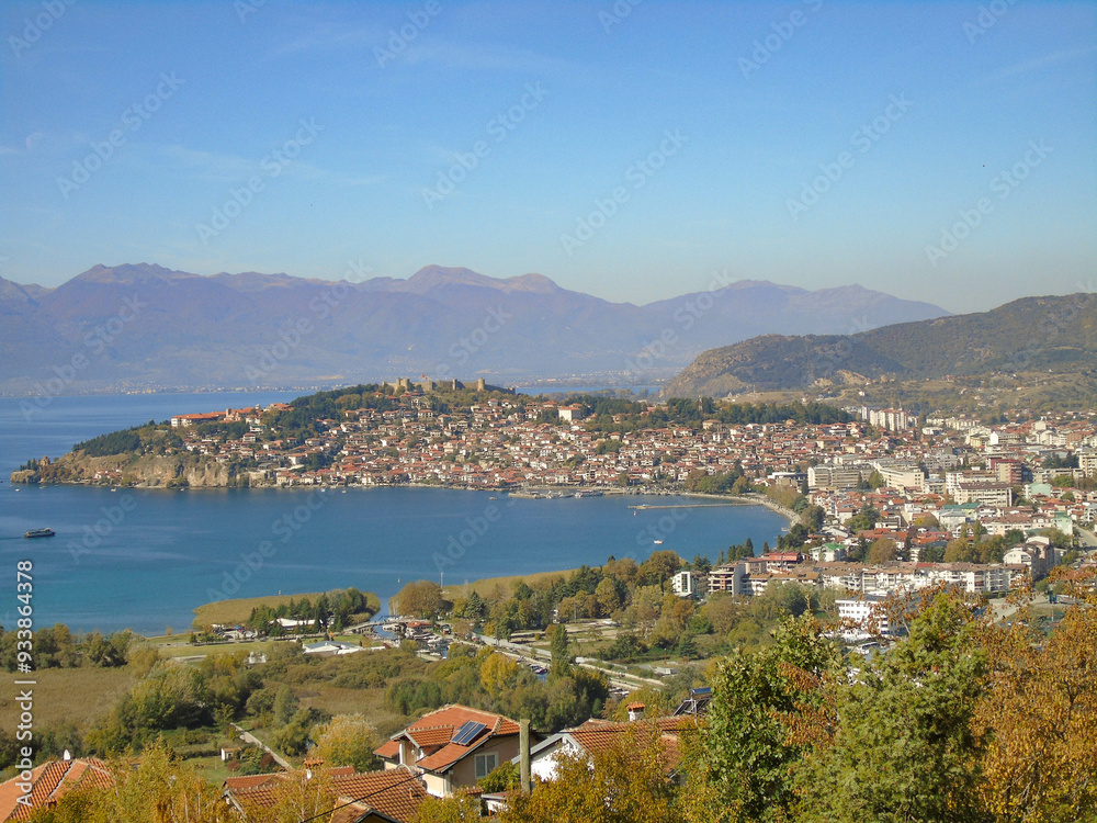 A scenic view out across Lake Ohrid to the town with mountains in the distance and under clear, blue skies A scenic view out across Lake Ohrid to the town with mountains in the distance and under clear, blue skies