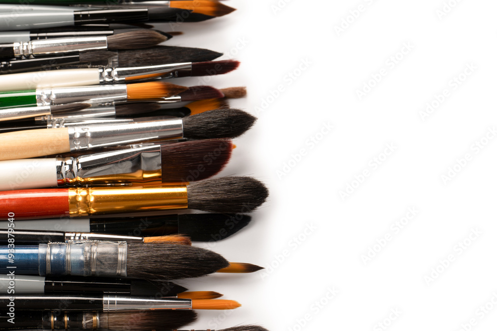 Fototapeta premium Mix of paint brushes in a row isolated on a white background. Top view.