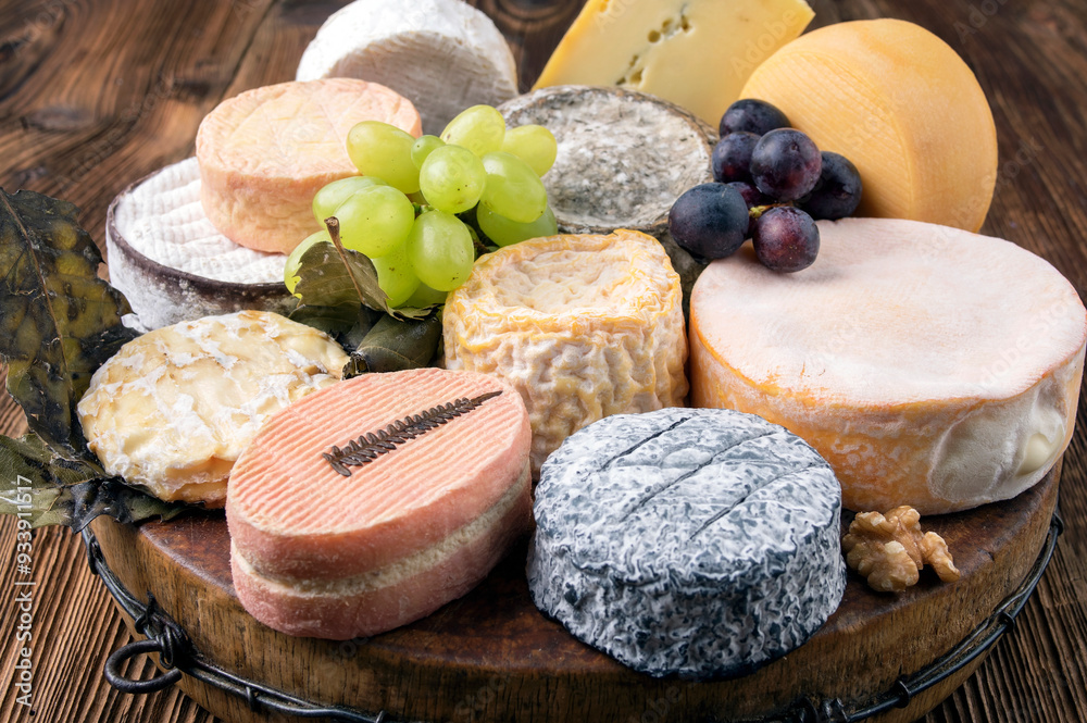 Traditional cheese platter with soft cheese and fruits served as close-up on a rustic wooden design board Traditional cheese platter with soft cheese and fruits served as close-up on a rustic wooden design board