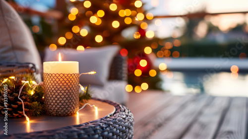 A cozy side table on a porch, enhanced with decorative lights and a candle for the Christmas celebration