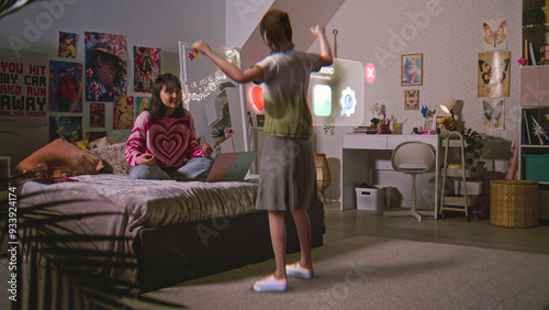 Teenager girl chats with virtual reality hologram in metaverse AI chat sitting on bed with laptop. Futuristic 3D graphics of animated avatar. Technology of AI friend simulation. Augmented reality.