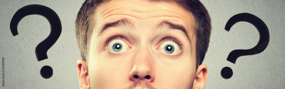 Naklejka premium Young man displays shock and confusion, eyes wide, mouth open, with question marks around him