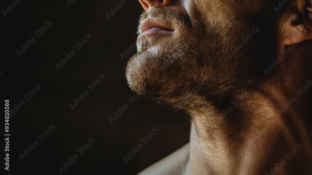 Obraz premium Close-up of a man's bearded neck and chin, with subtle lighting enhancing the texture and contours of his skin and hair.