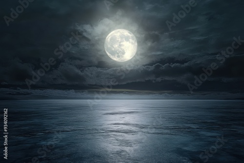 A serene full moon illuminates a calm ocean under a cloudy night sky.