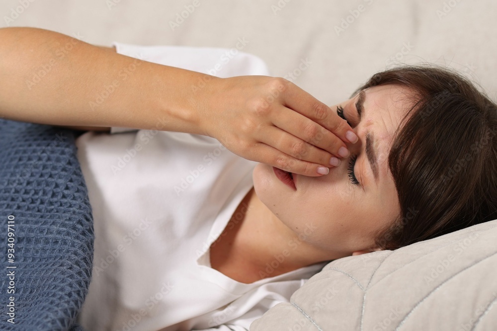 Tired woman suffering from sinusitis on sofa at home Tired woman suffering from sinusitis on sofa at home