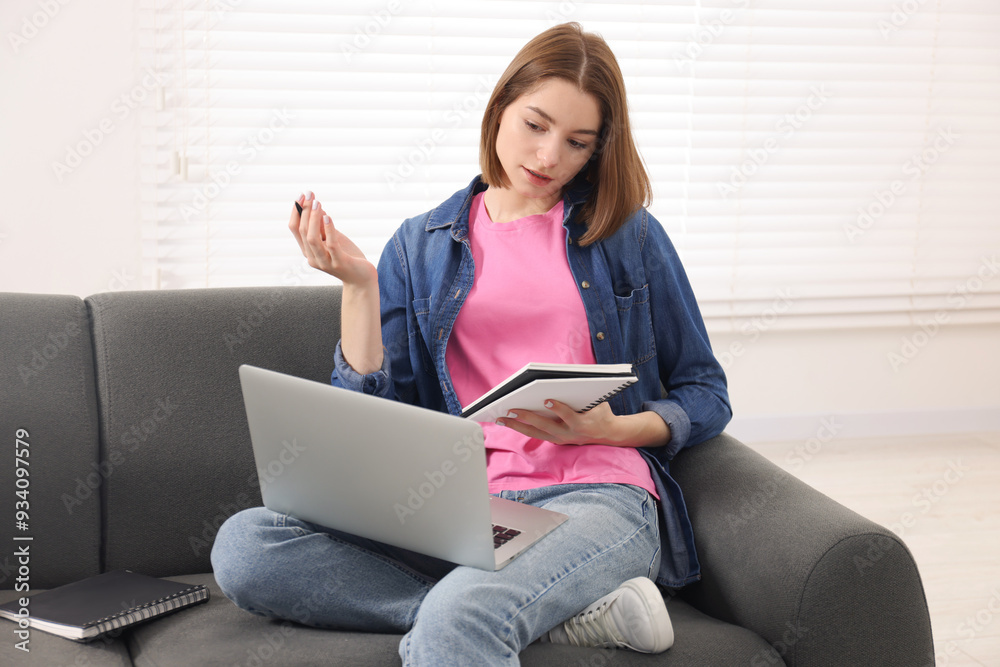 Teenager taking notes while working with laptop at home. Remote job Teenager taking notes while working with laptop at home. Remote job