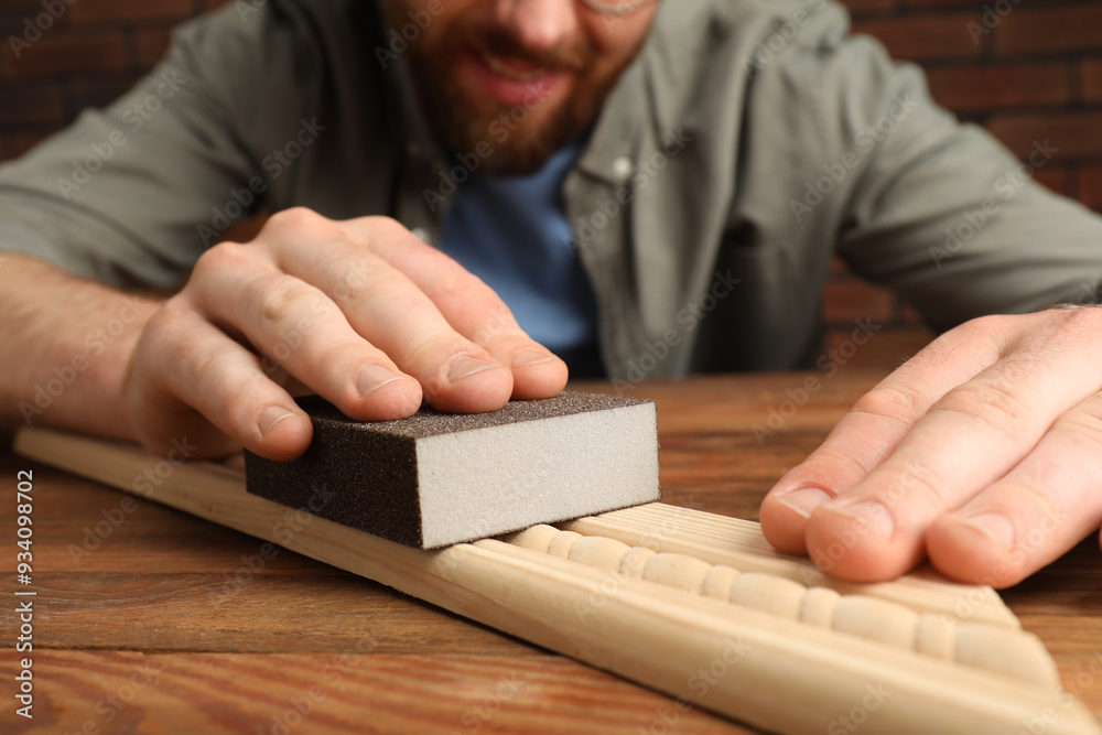 Man polishing wooden plank with sandpaper at table, closeup Man polishing wooden plank with sandpaper at table, closeup