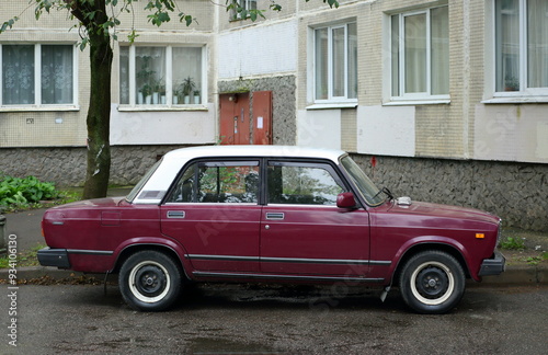An old red Soviet car with a white roof in the courtyard of a residential building, Kollontai Street, St. Petersburg, Russia, August 22, 2024