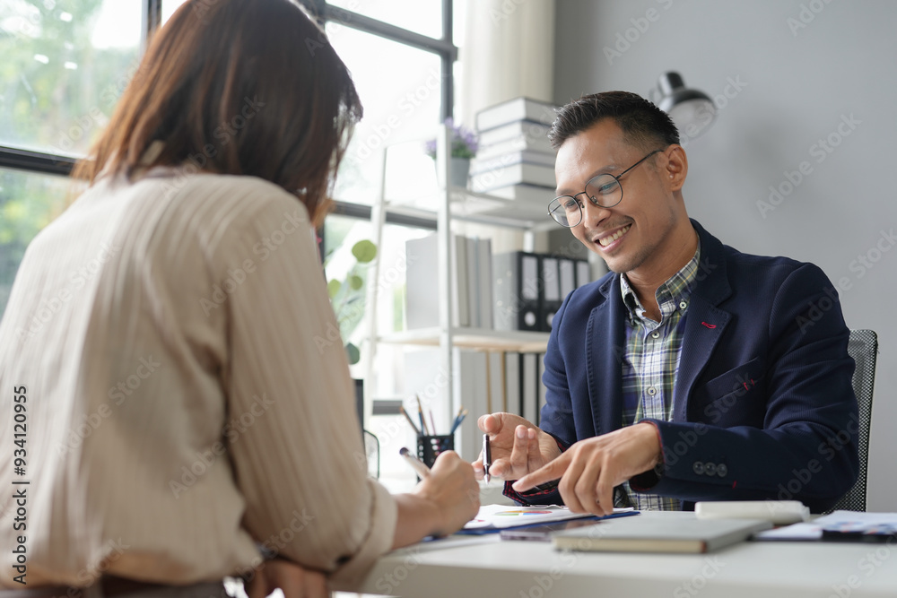 Businessman is pointing to a document while explaining something to his female colleague Businessman is pointing to a document while explaining something to his female colleague