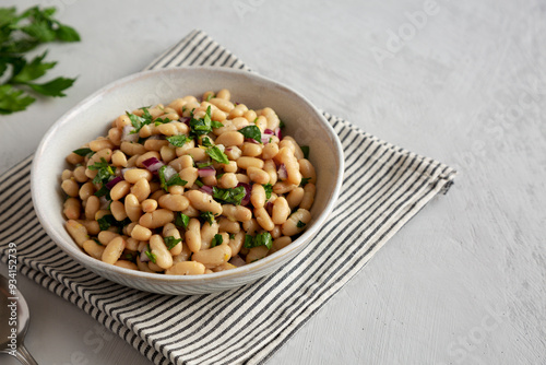 Homemade White Bean Salad with Herbs and Onion in a Bowl, side view. Copy space.