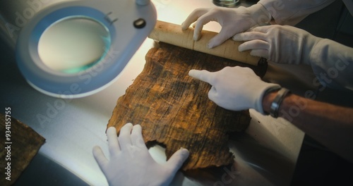 Scientists examine and discover cultural heritage of extinct human civilization. Two archaeologists in gloves carefully open ancient Egyptian papyrus on the table in archaeological lab. Archaeology.