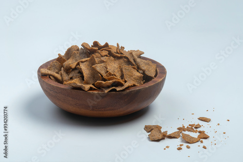 Indian snack Nachni Chips in a carved wooden bowl, isolated on white photo