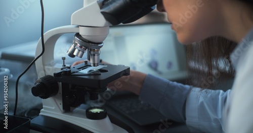 Obraz na plátne Close up of young scientist using microscope, analyzing sample in archaeological or medical science laboratory, looking at laptop screen