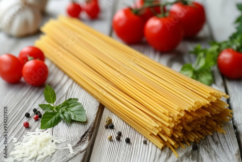 Uncooked spaghetti with fresh tomatoes, basil, garlic, and spices on a wooden table.