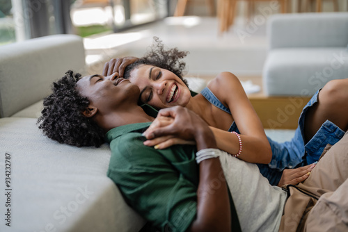 Slika na platnu A young couple, relaxed and affectionate, cuddle on a cozy couch