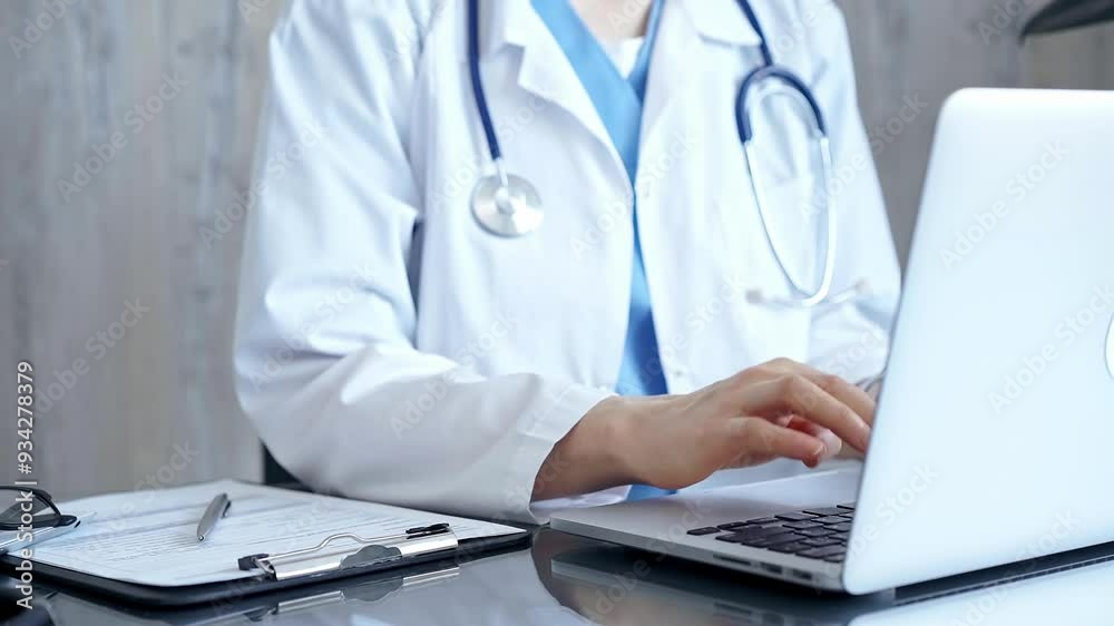 Doctor is using laptop computer in clinic office while sitting at the glass desk. Medicine concept Doctor is using laptop computer in clinic office while sitting at the glass desk. Medicine concept