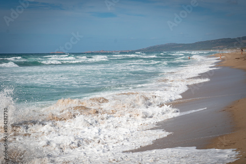 In Sardegna una spiaggia con la sabbia gialla e onde alte in estate. photo