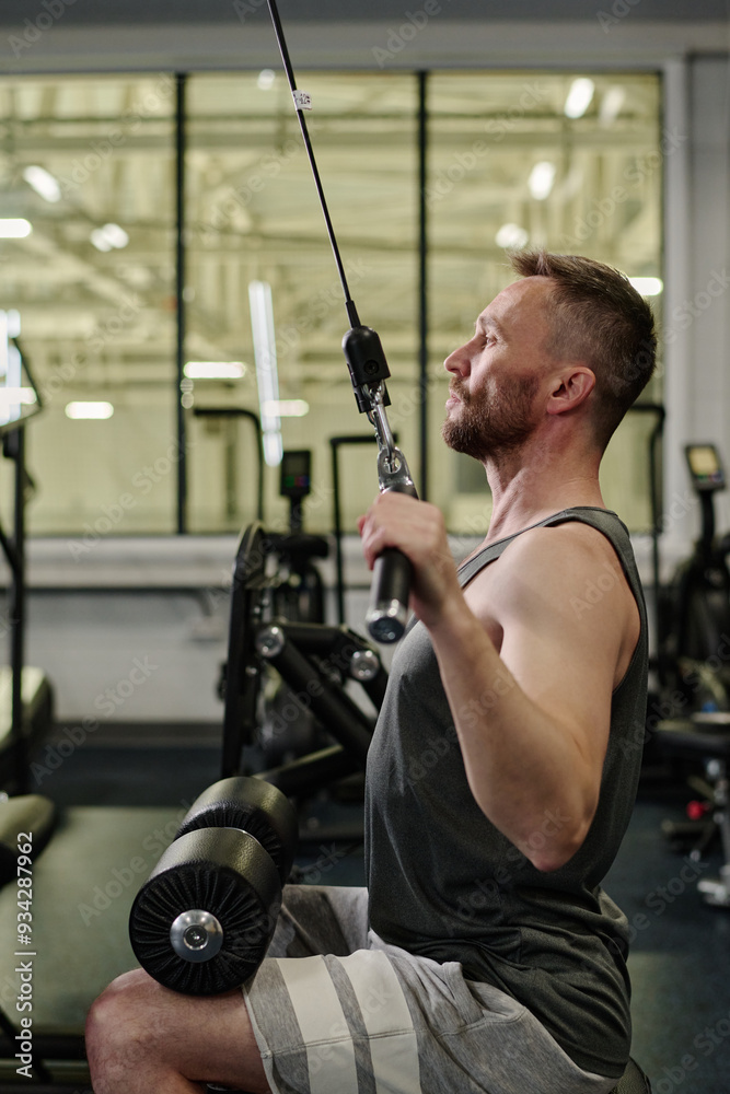 Side view shot of man using weight machine to gain muscles Side view shot of man using weight machine to gain muscles
