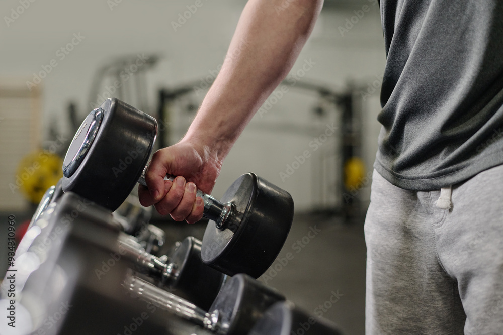 Medium close up of unrecognizable male hand holding heavy rubberized dumbbell