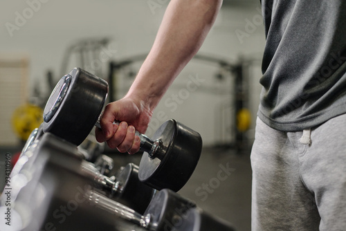 Medium close up of unrecognizable male hand holding heavy rubberized dumbbell