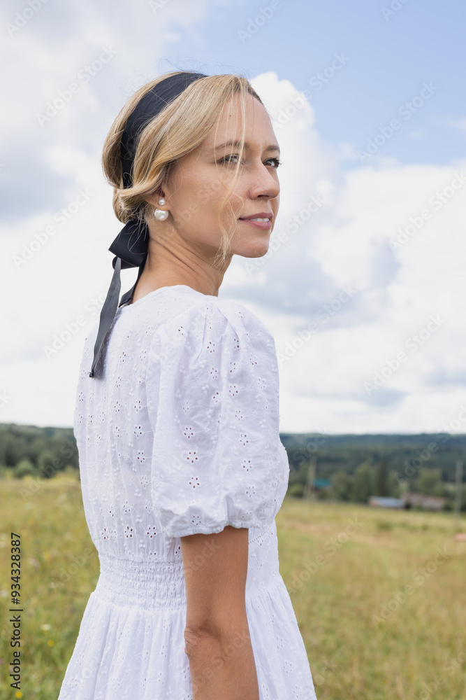 young woman looking to the right standing on a green meadow in summer young woman looking to the right standing on a green meadow in summer