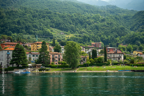 Mandello del Lario, Italy - June 08, 2024: A small beach near a small village on lake Como with mountains in the background.