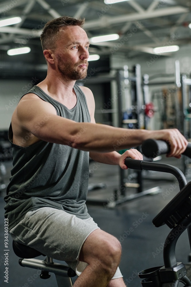 Sporty man doing cardio on exercise bike in popular fitness club Sporty man doing cardio on exercise bike in popular fitness club